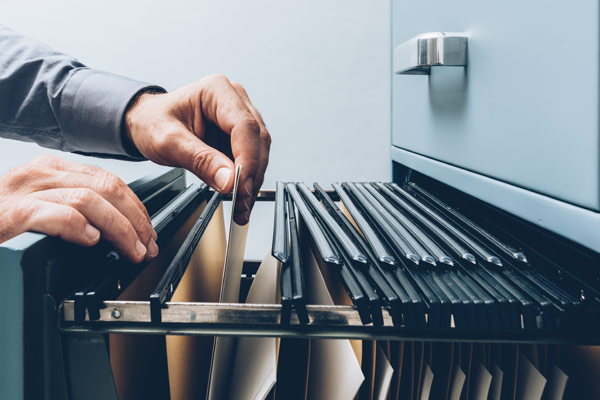 hand sorting through folders in a file cabinet